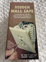 Photo of the Hidden Wall Safe packaging showing the fake electrical outlet with a pearl necklace inside the compartment.