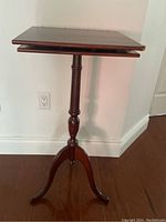 Front view of the darkwood music stand showing rectangular top and tripod base against light wall.