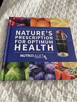 Front cover of 'Nature's Prescription for Optimum Health' NutriBullet Rx hardcover book showing colorful fruits and NutriBullet blender image.