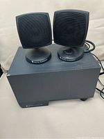 Two small cube speakers placed on top of a black subwoofer unit, all black with Altec Lansing branding visible.