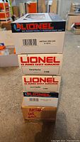 Stack of four Lionel train model boxes showing box car and ore car model numbers and branding.