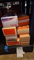 Stack of boxed Lionel train pieces with model numbers and rail names visible.