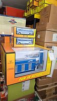 Stack of items showing the large Greyhound Station box on bottom with two smaller boxes containing the die cast buses on top, all RailKing branded.