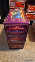 Stack of three purple M.T.H. Electric Trains boxes showing side with Conrail 8000 gallon tank car label on top box.
