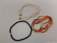 Top view of 3 chokers on a flat surface showing rose quartz, carnelian, and amethyst beads