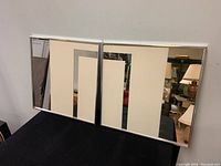 Pair of Greg Copeland Mid-Century Modern mirrored wall art pieces displayed side by side, showing full front view with reflective surfaces and chrome frames.