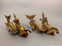 Pair of old Thai mythical dragon wood sculptures side by side showing gold finish and green accents.