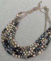 Close-up image of the necklace showing layers of multi-coloured baroque freshwater pearls and silver chains.