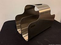 Front angled view of stainless steel magazine rack with curved shape and Blomus label.