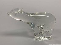 Side angle view of clear crystal polar bear sculpture on white background, showing smooth rounded form and crystal clarity.