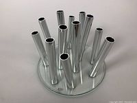 Top view of the chrome tubes on a round glass base showing the arrangement and reflective finish.