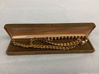 Gold-toned choker and bracelet displayed in a brown velvet-lined jewelry box showing the set together.