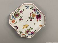 Top view of the ceramic serving bowl showing floral design on white background with scalloped edges and pink rim line.
