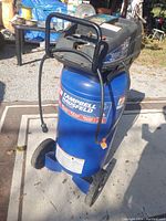 Front three-quarter view showing tank, wheels, handle, control panel and branded label