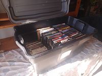Overview of black plastic storage bin filled with DVDs on two layers
