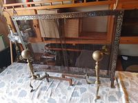 Metal mesh fireplace screen with embossed decorative frame, showing minor corrosion.
