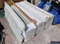 Photo of three sealed boxes each containing backsplash tiles, showing typical box packaging and white tile edges visible at openings.