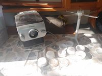 Full view of the Philips electric pasta maker with attached power cord, multiple white plastic pasta shaping discs arranged in front, and a white pasta drying rack.
