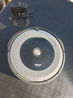 Top view of iRobot Roomba robot vacuum with charging dock and power adapter placed on top.
