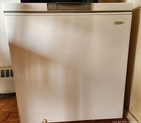 Front view of white Danby chest freezer showing no visible damage, handle at top edge, and a small round knob near bottom left.