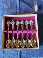 Set of six silver spoons in purple velvet-lined box, showing full set.