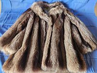 Front and spread view of the raccoon fur coat showing texture, fur pattern, collar, and length.