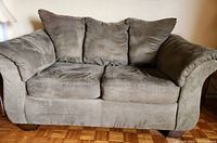 Front view of a grey loveseat sofa with two seat cushions and three back cushions, wide armrests, wooden legs, shown indoors on parquet floor.