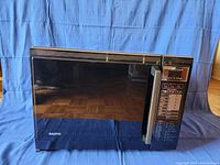 Front view of a black Sanyo microwave showing entire exterior and door with handle.