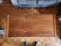 Top-down view of teak living room table showing surface wear, faded areas and stains.