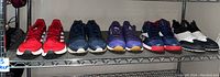 Five pairs of size 11 sneakers on wire shelf, various colors and brands including Adidas and Reebok.