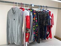 Gray knit quarter-zip sweater and assorted colorful button-up shirts and pullovers hanging on a rack