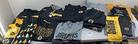 Wide image showing all Boston Bruins apparel items laid out on a table including hoodies, sweaters, pullovers, polos, windbreaker, shorts, sweatpants, and towel.