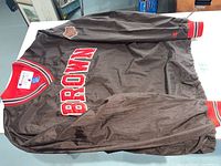 Full front view of brown pullover nylon jacket with Brown University logo and patches