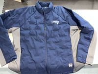 Front view of navy blue and gray lightweight NFL jacket with New England Patriots logo on left chest.