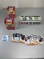 Photo showing two sealed red Sage NFL Trading Cards boxes, one sealed Panini Donruss NFL box (400 cards), and multiple opened trading cards including an autograph card.