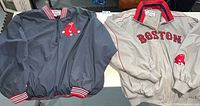 Both jackets laid flat, showing the front of each including team logos and jacket materials