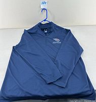 Front view of navy blue Tennessee Titans 1/4 zip pullover laid flat on white surface.