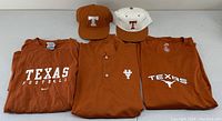View of two Texas Longhorns fitted hats and three shirts, all burnt orange themed with various logos and text related to Texas Football and University of Texas.