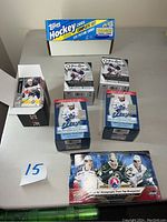 Full view of unopened boxes of 2022-2023 O-Pee-Chee AHL hockey cards and the complete 1992 Topps hockey card set in box on table.