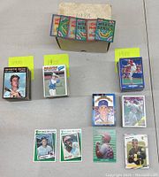 Photo of multiple stacks of vintage baseball cards labeled 1970, 1977, 1988, showing variety of cards including holographic and individual player cards.