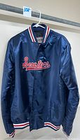 Front view showing navy blue satin jacket with 'Senators' embroidered in red and white, striped ribbed collar, cuffs, and waistband.