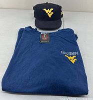 Combined photo showing the folded 2XL navy blue t-shirt with WV logo and the fitted WV hat placed behind it.
