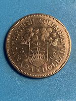 Reverse side of 1971 Canadian silver dollar coin with British Columbia coat of arms and inscriptions.