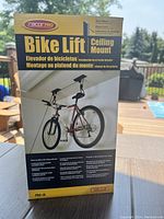 Photo of the Racor Pro Bike Lift box showing the product as a ceiling mount bicycle lift system with a bike suspended.