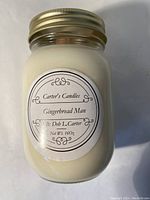 Glass mason jar candle with cream white wax and metal lid, label reading Carter's Candles Gingerbread Man with personalization.