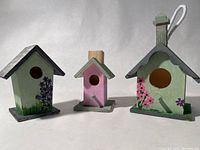 Three miniature hand painted bird houses in different colors and floral designs