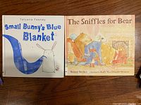 Photo of Small Bunny's Blue Blanket and The Sniffles for Bear books laid flat on a wooden surface