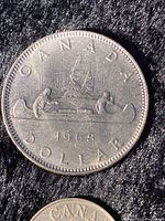 Close-up image of 1968 Canadian silver dollar featuring voyageurs in a canoe.