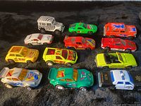 Top view of the dozen toy cars showing variety in colors and styles including off-road, police, race cars and vintage style.