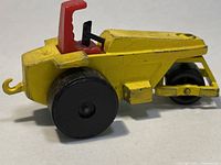Yellow rod roller toy vehicle with black wheels and red seat, angled view showing details and condition.